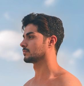 Profile of a contemplative young man against a tranquil blue sky in Baghdad, Iraq.